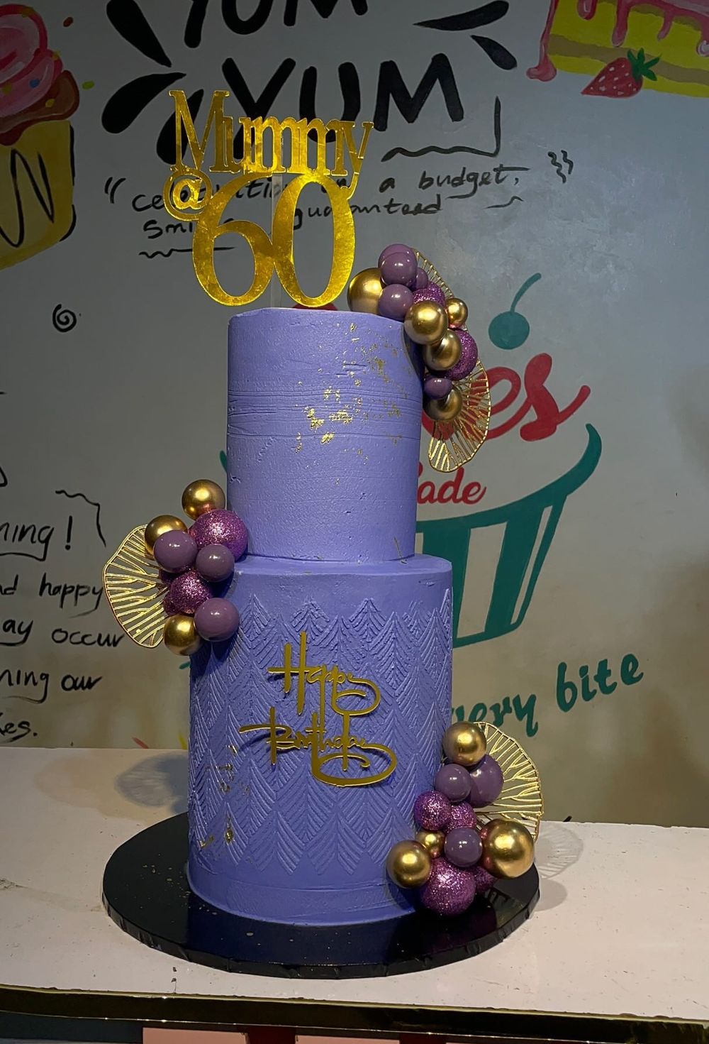 Purple and white celebration cake decorated with gold balls, by Cakes by Sadee